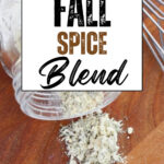 Glass jar tipped on a wooden board spilling a dried herb seasoning beside a whisk. Text reads Copycat Fall Spice Blend.